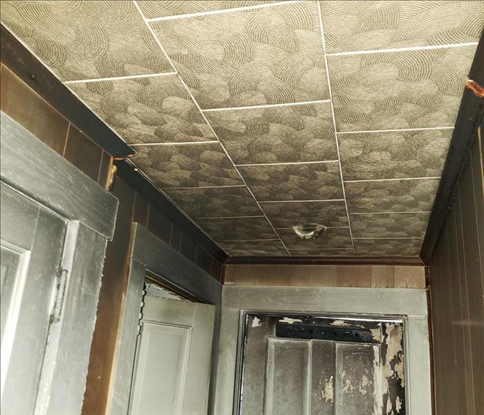 Hallway with textured ceiling tiles with fire and smoke damage