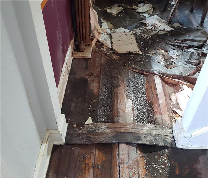 Buckled wood floorboards with muddy water and debris