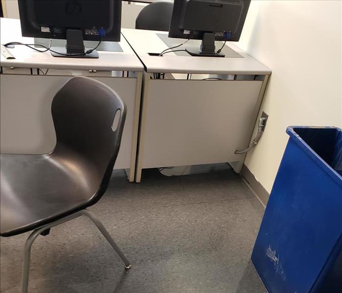 Chair beside desks and monitors on a tile floor