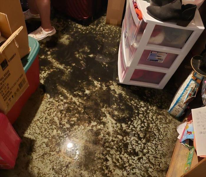 Basement with contaminated water on the floor beside stored items